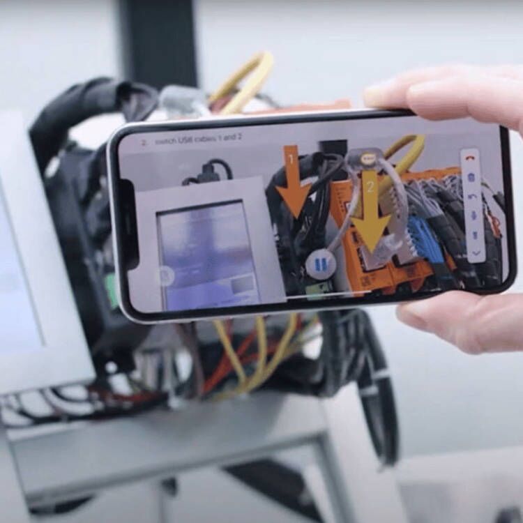 Ein Smartphone wird verwendet, um mit der TeamViewer Assist AR-Anwendung technische Anweisungen zur Verkabelung eines Etikettiersystems zu visualisieren und Fehler zu beheben.
