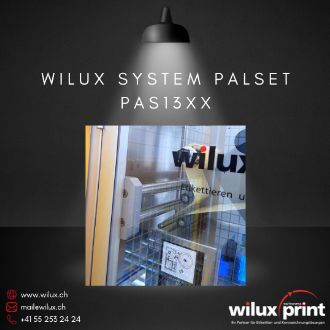 Nahaufnahme des Inline Thermotransferdruckers im WILUX System PalSet PAS13XX. Der Drucker befindet sich hinter einer schützenden Glastür, während der Etikettierprozess stattfindet.