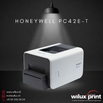 Honeywell PC42E-T Desktop-Etikettendrucker in weissem Gehäuse, Schrägansicht von vorne rechts zeigt Etikettenausgabeschlitz, kompakte Bauweise und geschlossenen Deckel mit Sichtfenster