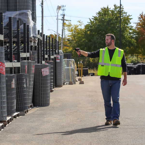 Employee in neon yellow safety vest uses the rugged scanner Honeywell Granit XP 1991iXR to scan pallets in the outdoor area