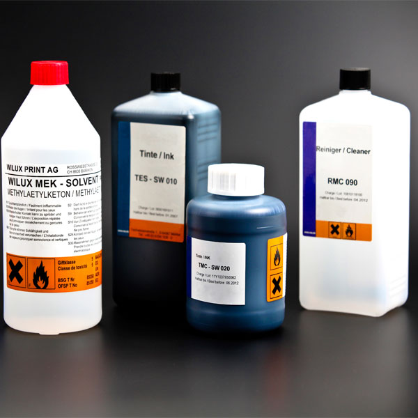 Ink-Jet Tinte, Solvent und Reiniger in blauen und weissen Flaschen für WILUX Ink-Jet-Geräte auf schwarzem Hintergrund
