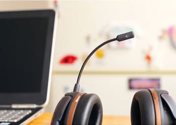 WILUX Kundendienst, Forschung und Entwicklung mit schwarzem Headset und schwarz/silbrigem Labtop auf hellbraunem Tisch