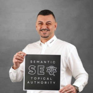 Özden Erdinc, Online Marketing Manager im Team WILUX PRINT, hält ein Poster mit der Aufschrift "Semantic SEO Topical Authority", gekleidet in einem weissen Hemd vor einem neutralen Hintergrund.